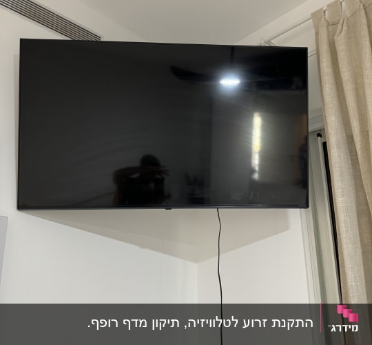 טלוויזיה תלויה על הקיר עם כבל חשמל גלוי